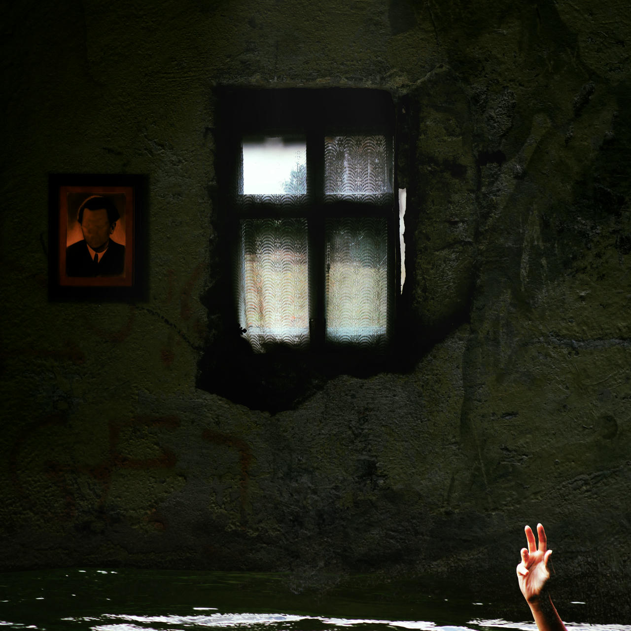 Inside a decaying room flooded knee-high. A hand is emerging from the water. On the wall at the back, there is a window of patterned glass, and a picture hanging to its left. The scene is lit by a hanging light-bulb.