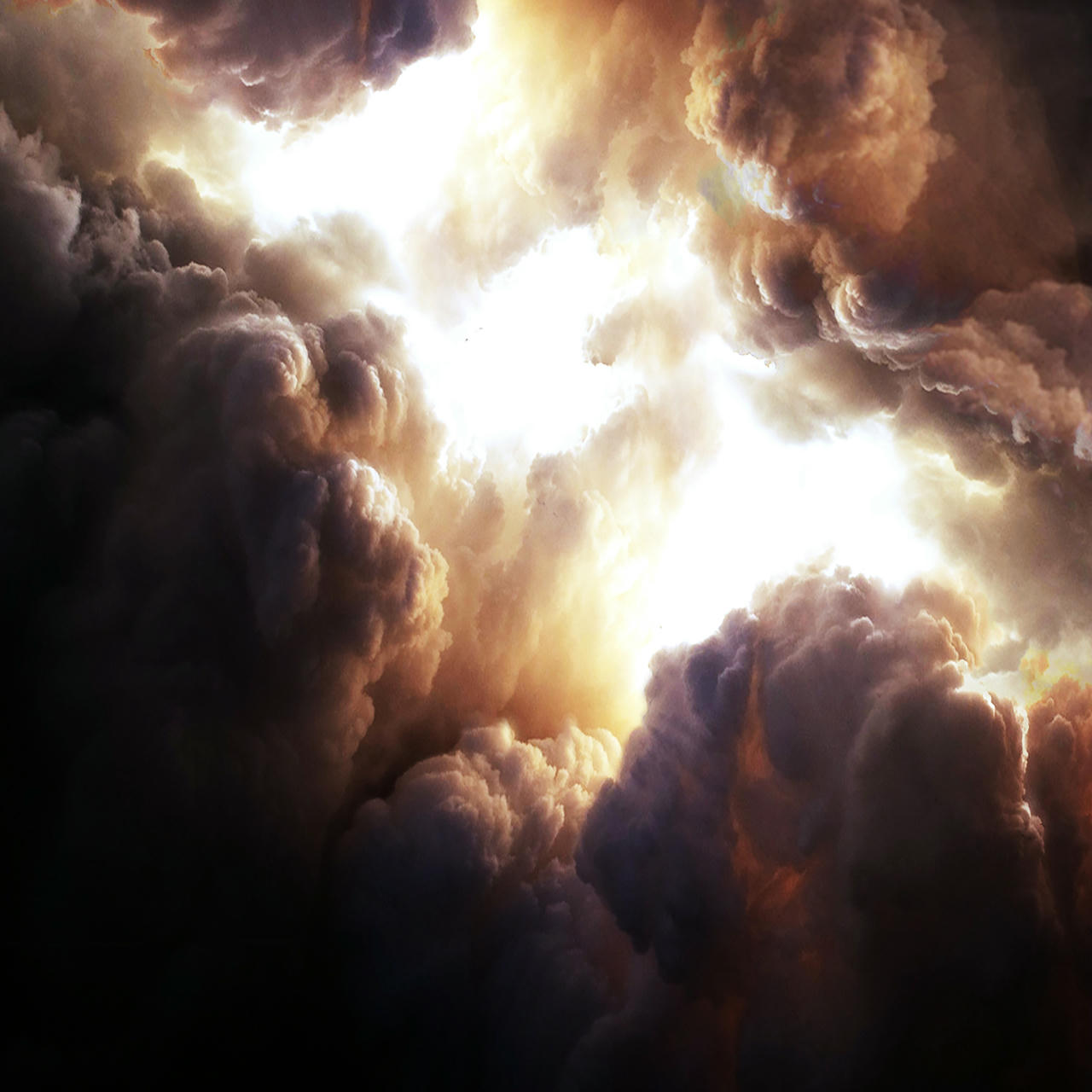 A very dramatic formation of cloud, with intense dark and light contrasts, over a vast, empty floor of large cement slates. A man is standing there.